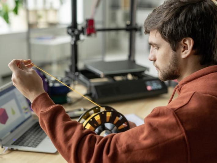 Chico joven sosteniendo bobina de filamentos para impresión 3D